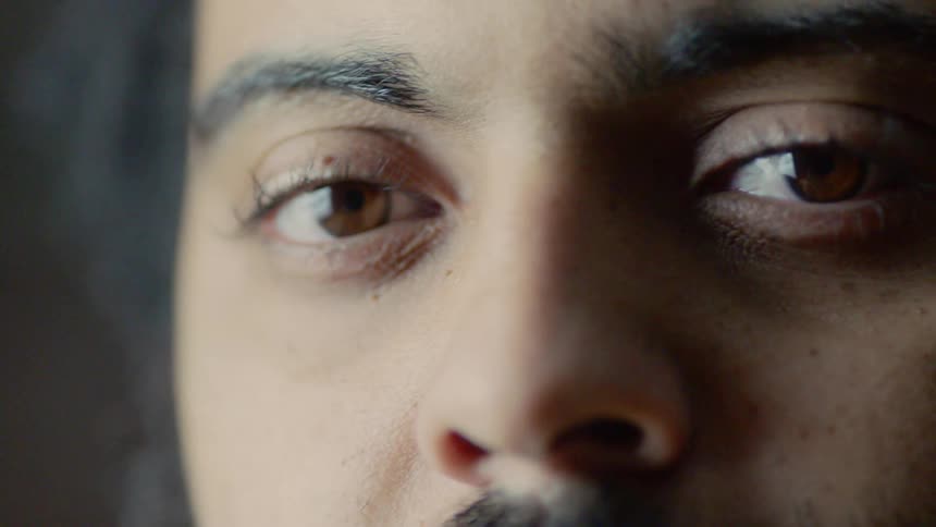 A man with a mustache and brown eyes looks forward