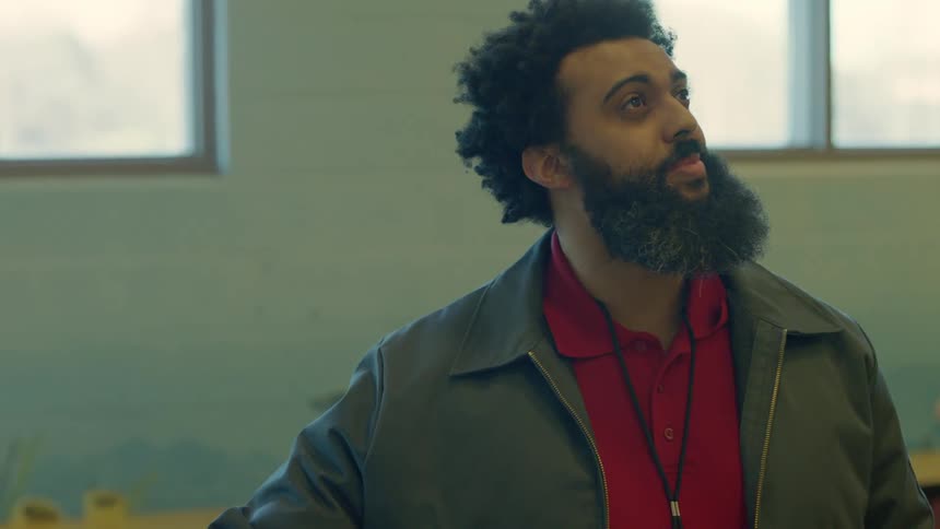 A man with a beard turns on a light in an large room