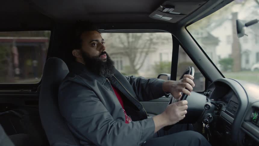 A male drives a car through a neighborhood and makes a right hand turn into a parking lot