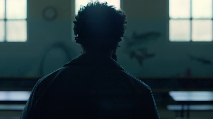 Man walks between rows of desks towards the windows