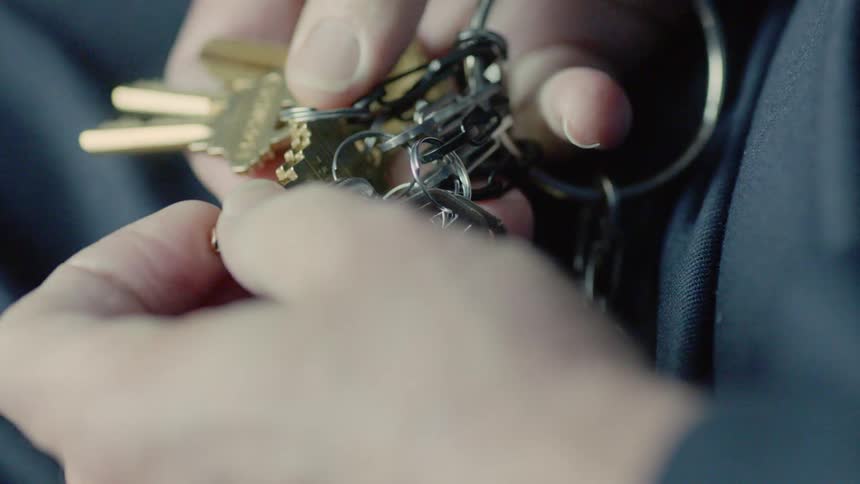 A woman looks through the keys on her keychain