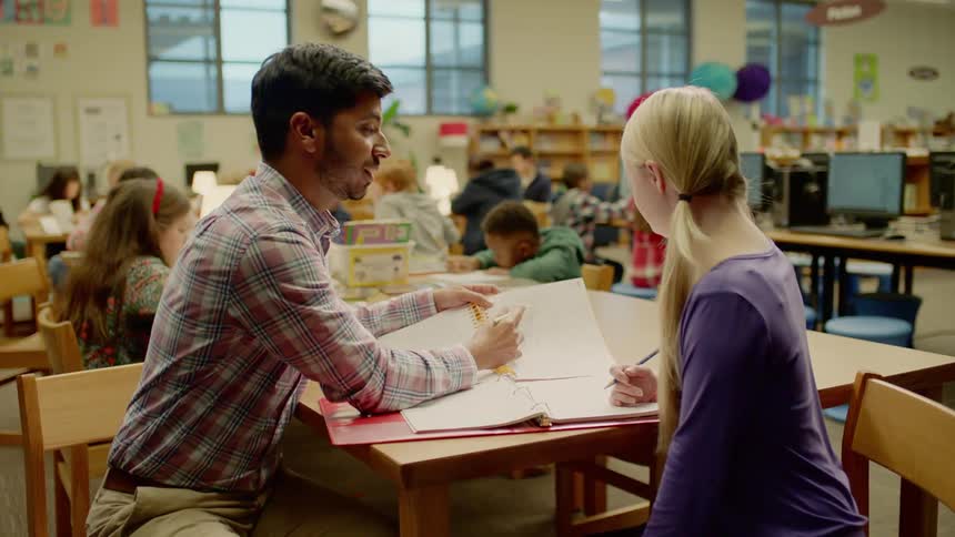 A young teacher helps a mentally challenged young white girl with learning material