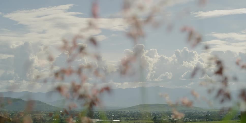 A sky full of fluffy white clouds can be seen high about a valley community