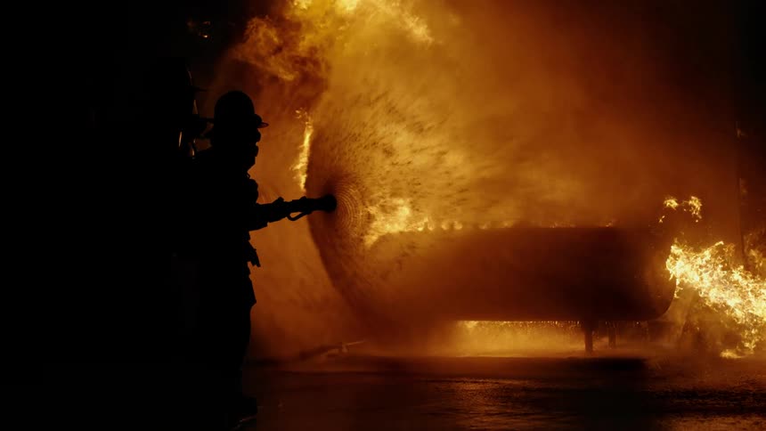 Silhouette of a fireman putting out a fire with a hose