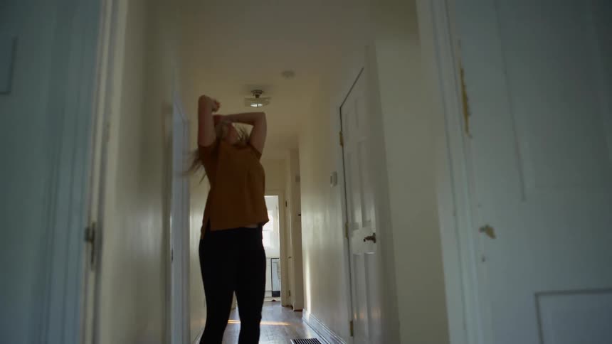 A white woman dances wildly in a houses hallway