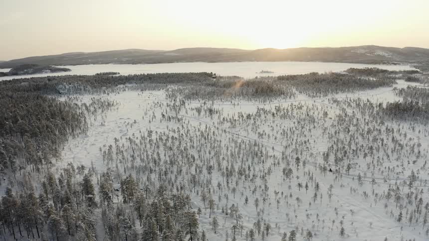 The sun is rising over the snow covered wilderness
