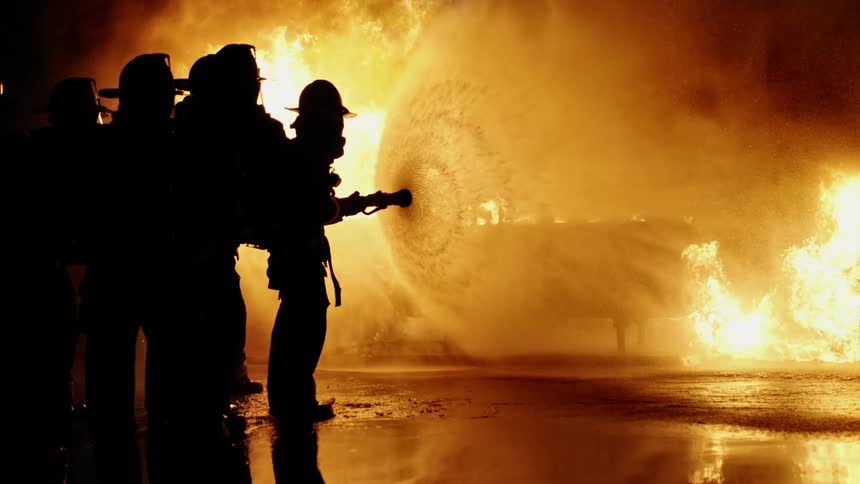 Firefighters aiming a hose at a large fire