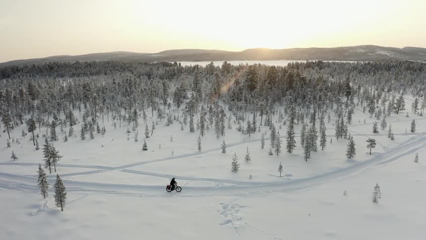 A person rides a bike on a snow covered path