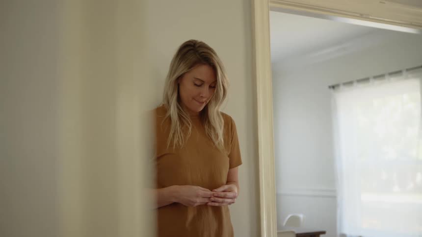 Blonde woman looking down stands in the corner of the room