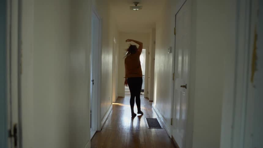 Woman dances in the hallway of her home