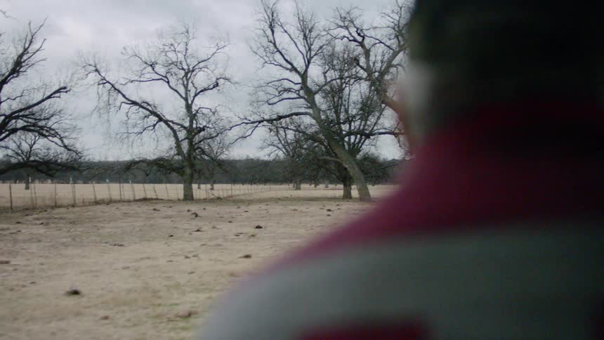 Interior view from car of a man driving near a field in the country
