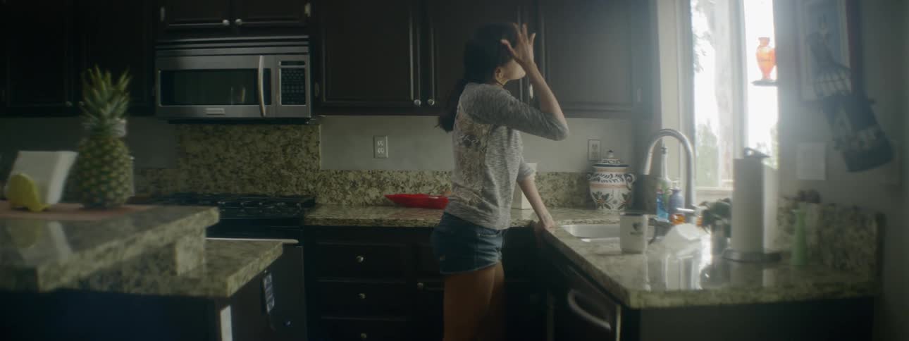 Woman takes break in kitchen after cleaning