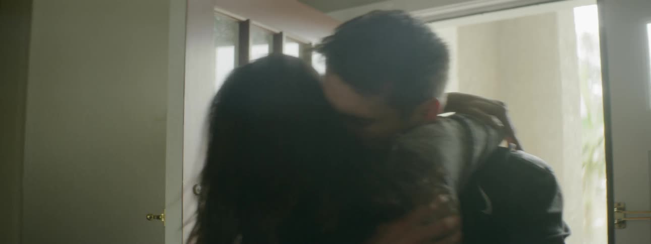 A female opens the front door to a home and hugs the man walking inside