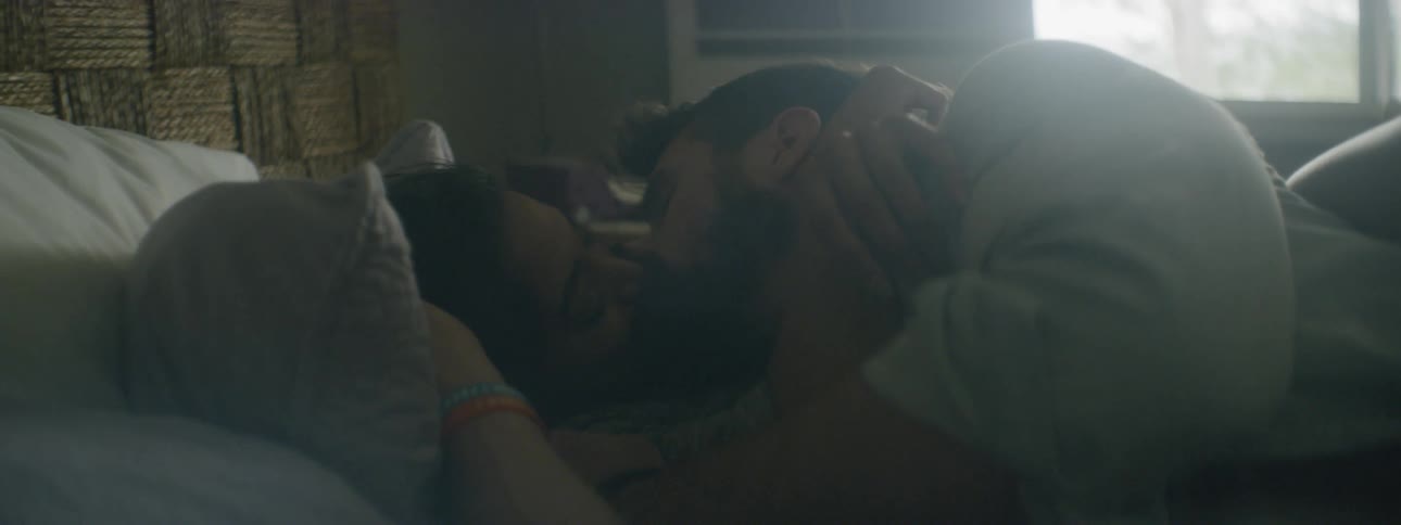 A man and woman kiss in bed
