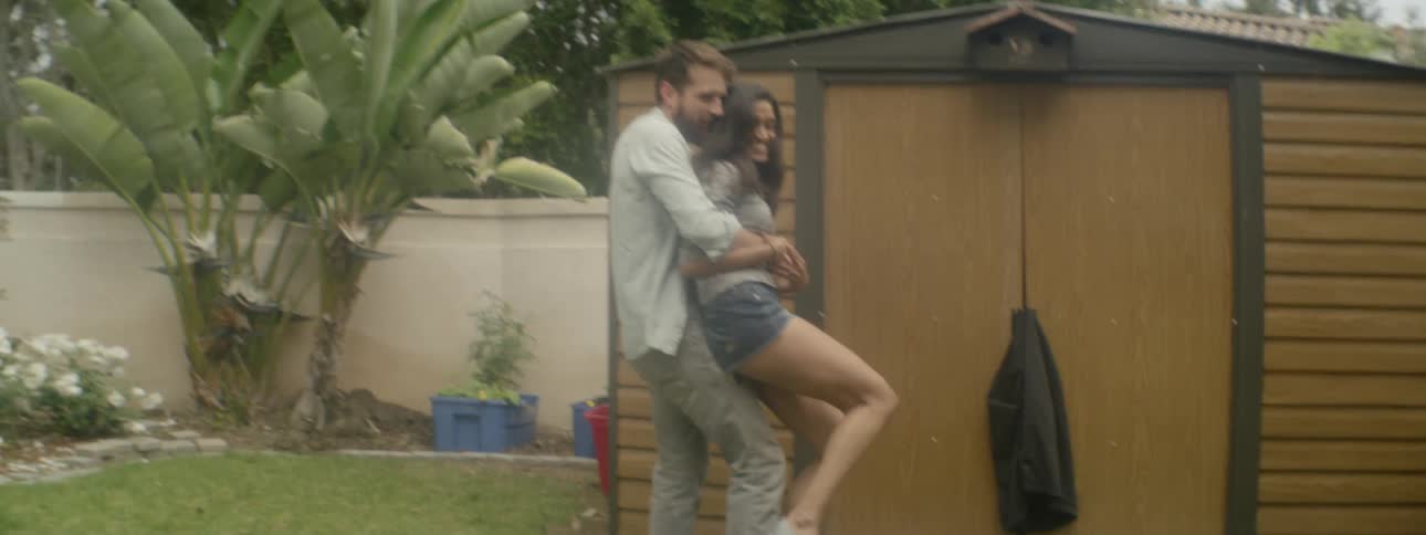 A man runs after a woman and picks her up and swings her around playfully