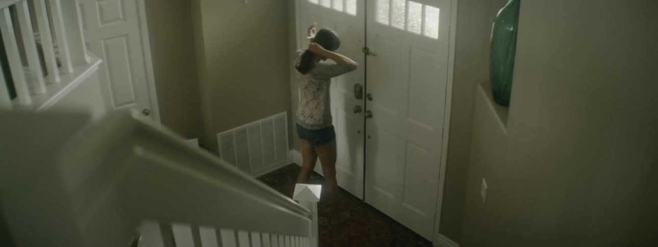 A woman walks down the stairs and answers the front door