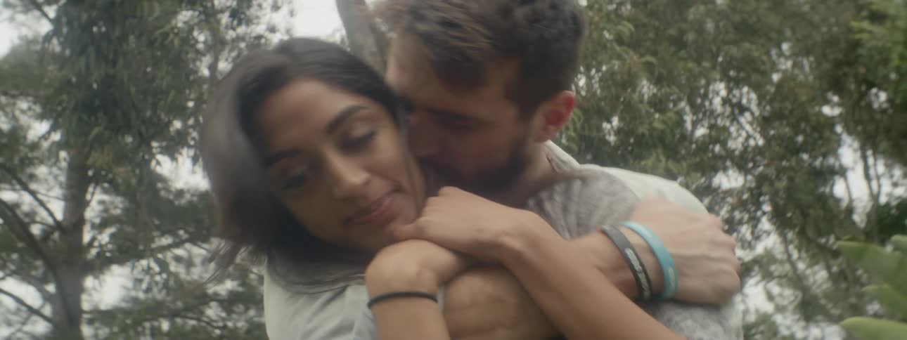 A man hugs a woman from behind in the forest