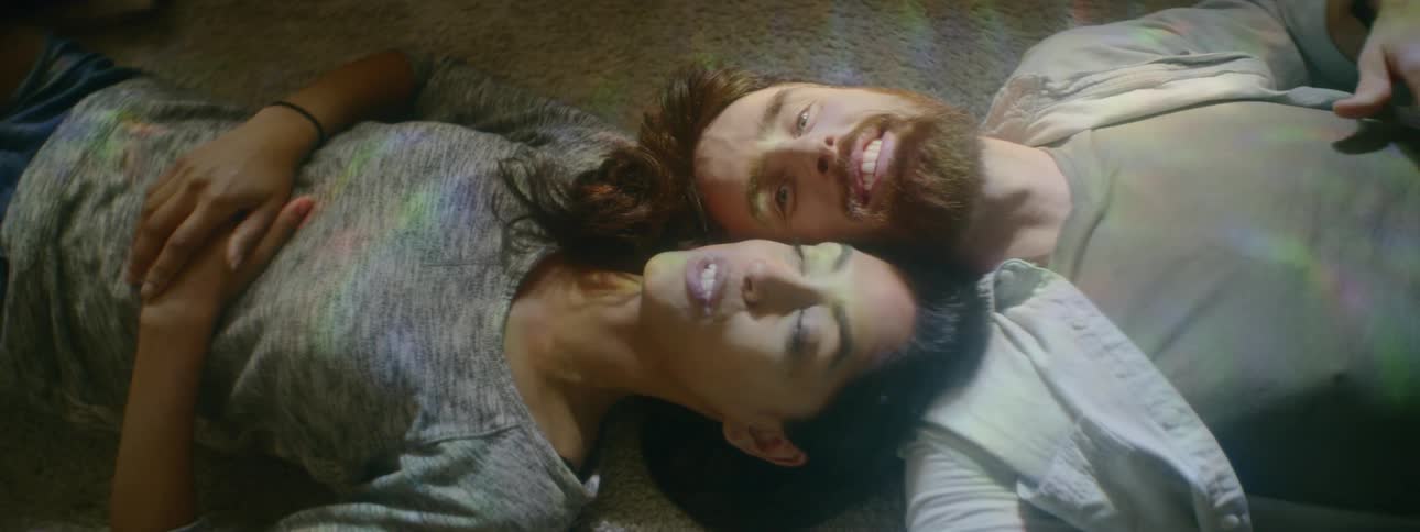 A man and a woman laying on the carpet head to head talking to each other