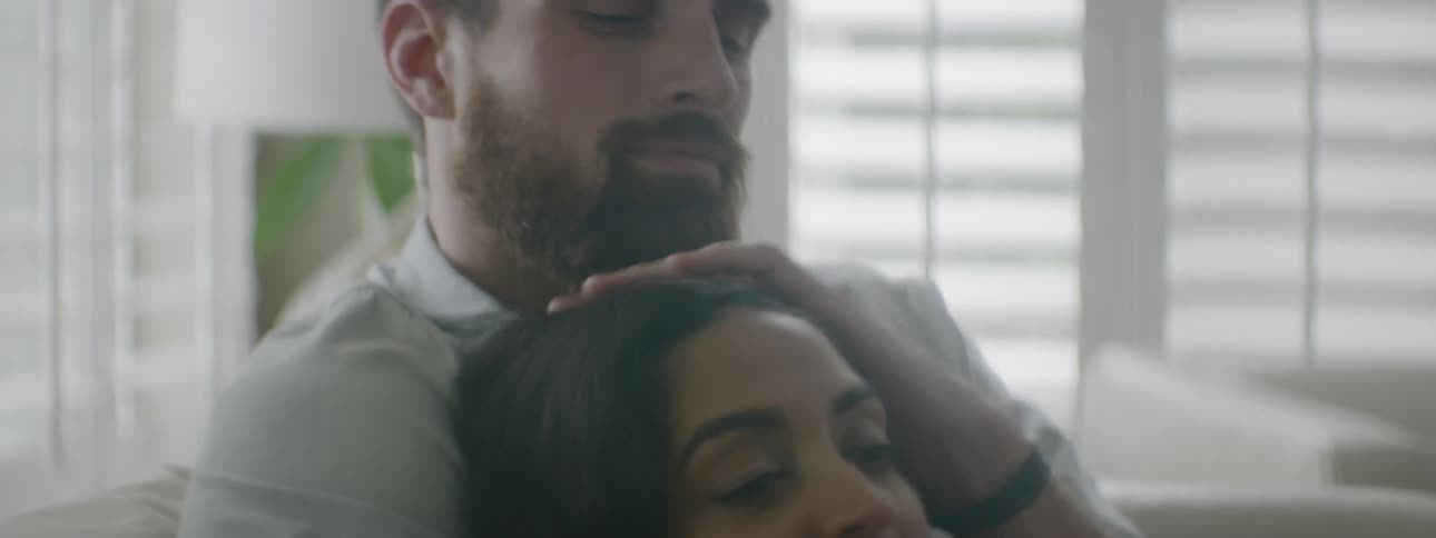 A man and woman sit together and cuddle on a couch