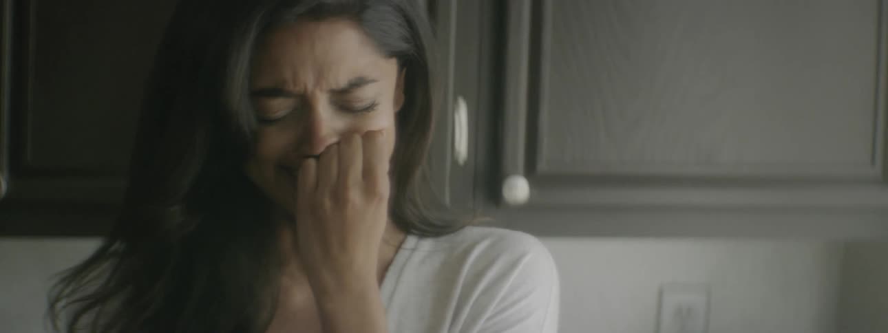 A woman crying while standing against cabinets