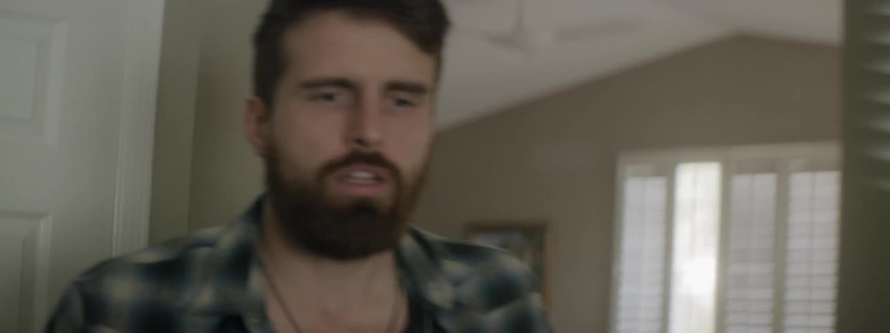 A frustrated man rising from his seat in a bedroom to talk to someone outside