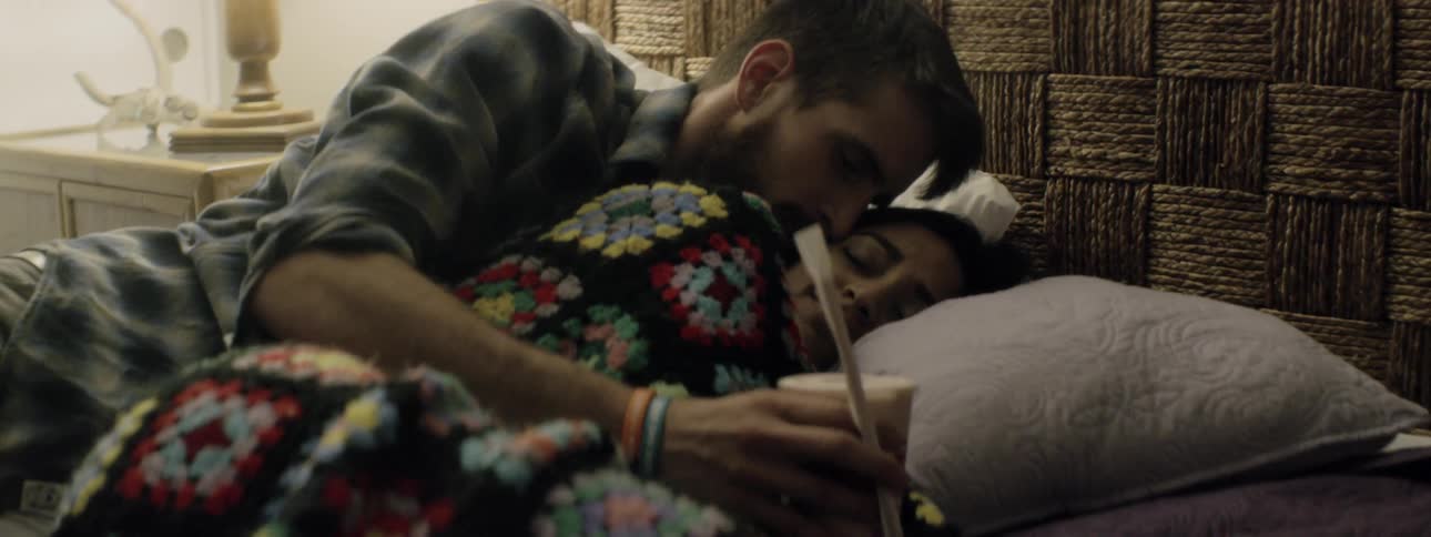 A man brings a woman a drink in bed