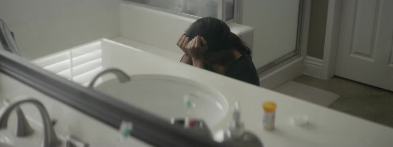 A woman sitting on the bathroom floor crying