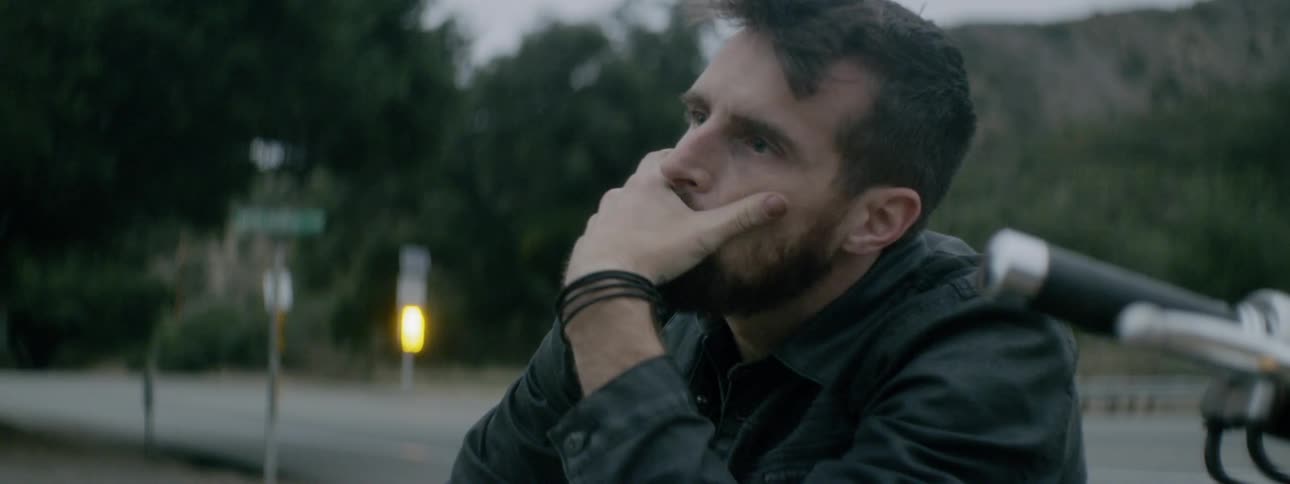 A man sits near the road