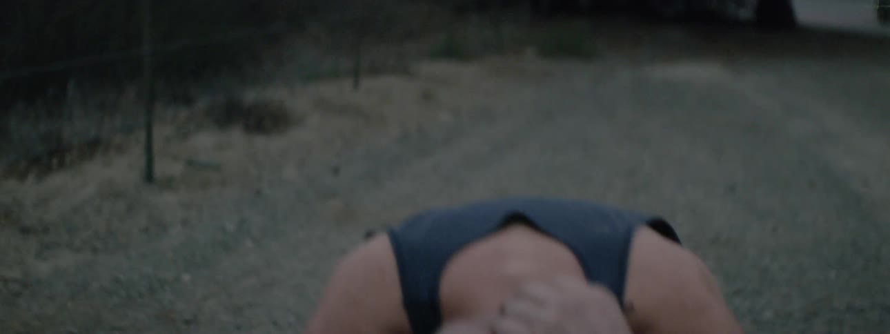 A man squats down on the ground with his arms covering his head in frustration