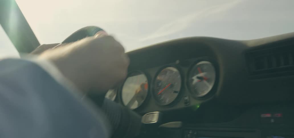 A driver controls the steering wheel and shifts gears as he races a sports car