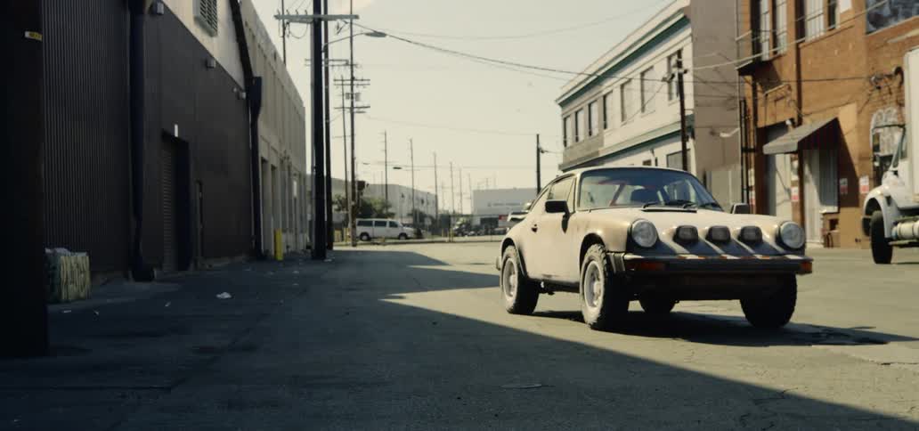 A vintage car sits alone in an alley way