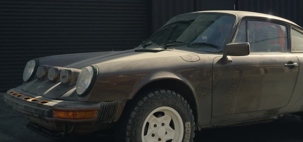 Dusty sports car is parked near garage door