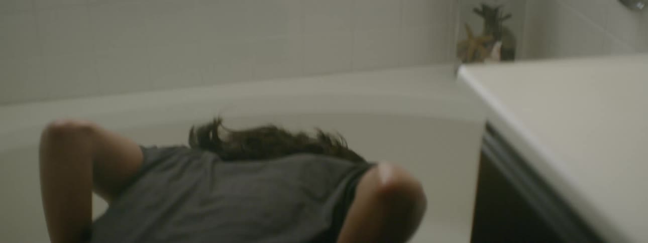 A woman vomits into a bathtub