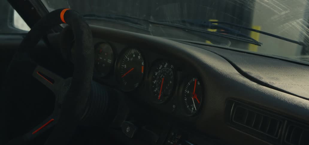 An interior of a car with a steering wheel and sunlight shining off the windshield