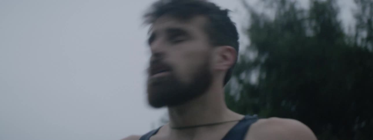 A man gets up from sitting on the ground outdoors and looks around
