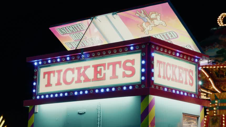 Bright and colorful lights change colors and flash around a ticket booth signboard