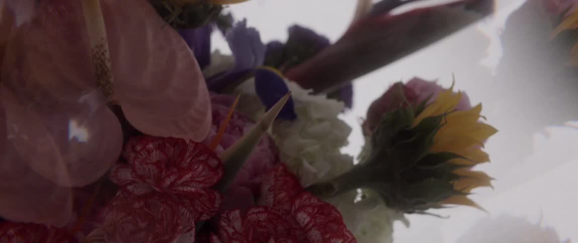 Lights flicker over a flower bouquet laying against reflective white surface