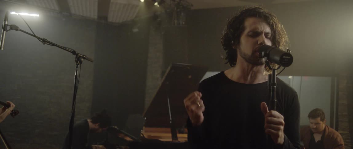A man singing as other men play instruments behind him