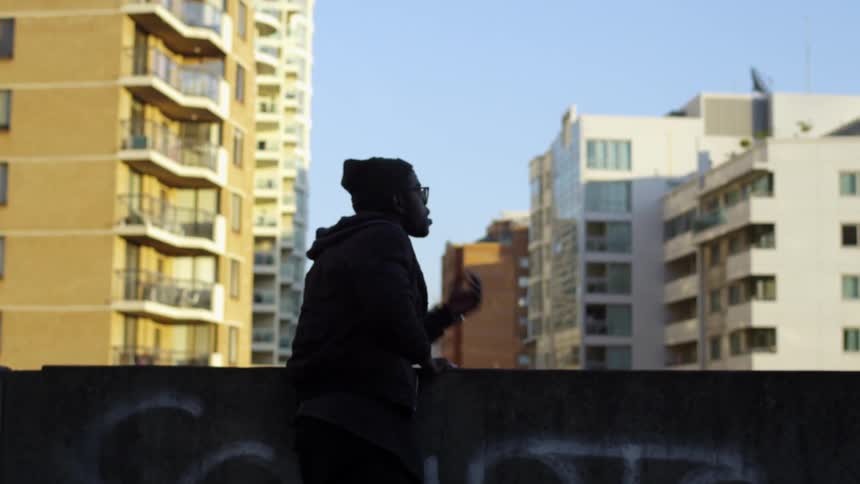 A man leans over a ledge and looks out at a city