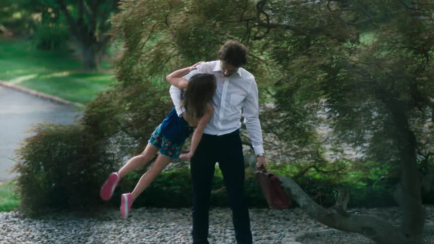 A man carrying a playing with a little girl as he walks towards his house