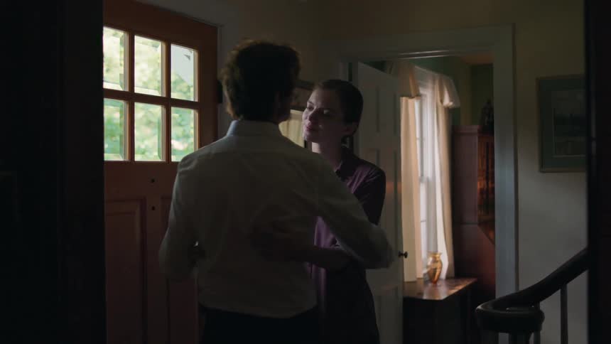 A man and woman embracing in the hallway of a house