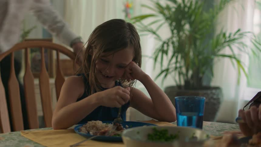 A girl smiling while stirring her food with a spoon
