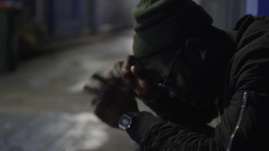 A man looking anxious in a city alley at night
