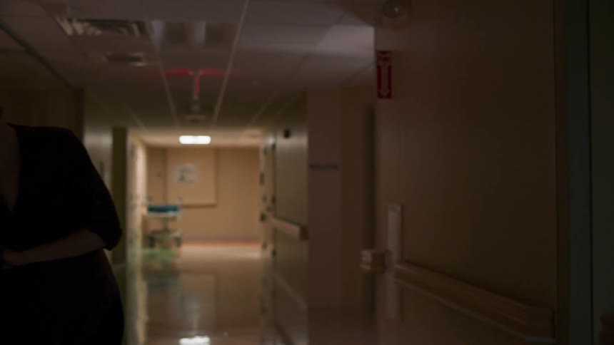 A woman walking in a hospital hallway than sitting down
