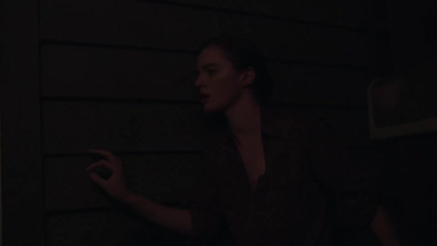 A woman stands against a wall and listens