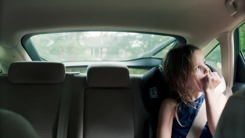 A little girl sitting in the backseat of a car