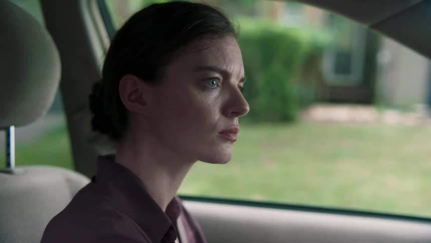 Blue eyed woman sitting in the car looks around anxiously