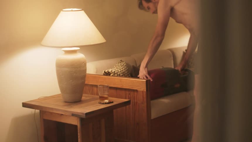 A man examining a leaf blower while standing in his boxers