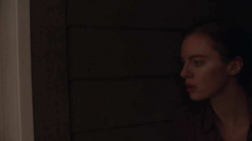 A white woman standing in the shadows suddenly cringes