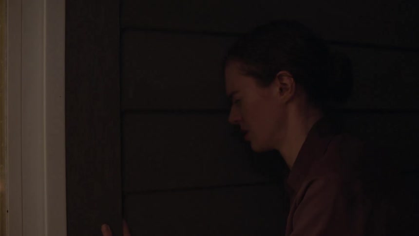 A woman winces as she slowly closes a door in her home